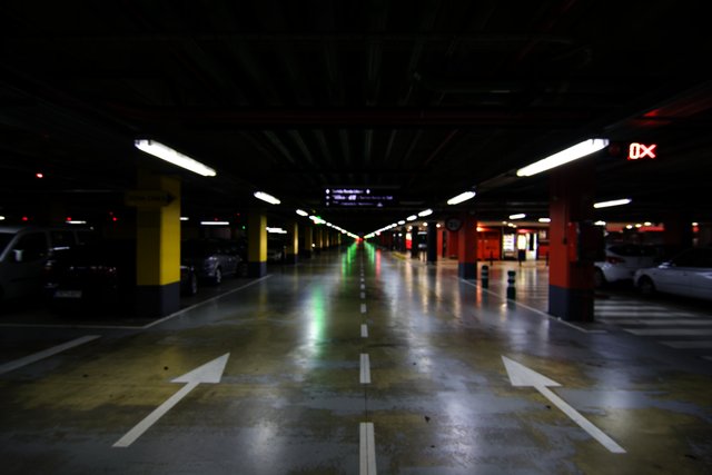 Empty underground car park, wet floor, painted arrows, receding fluorescent lights