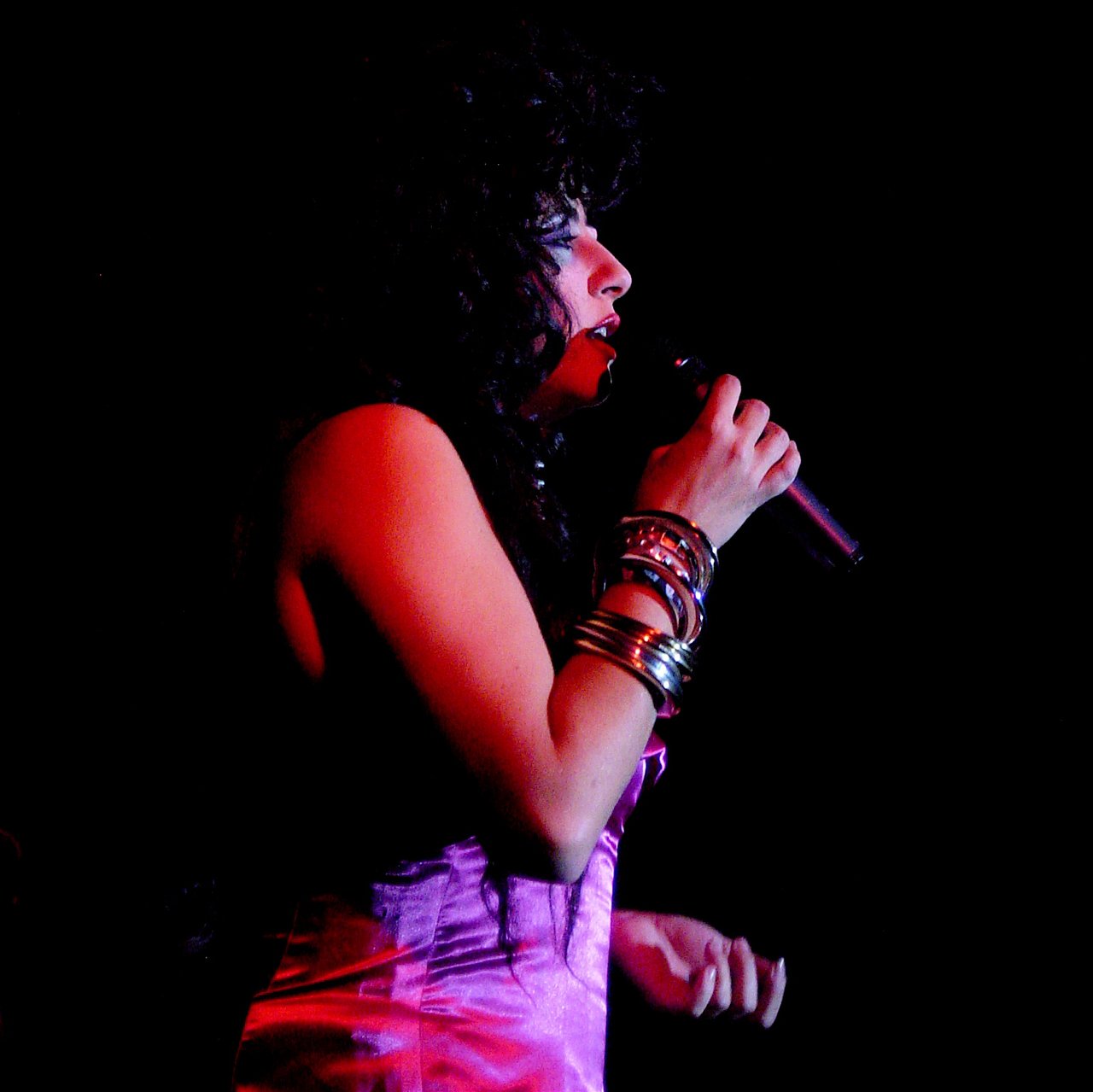 La Terremoto de Alcorcón singing in red stage light, microphone in hand