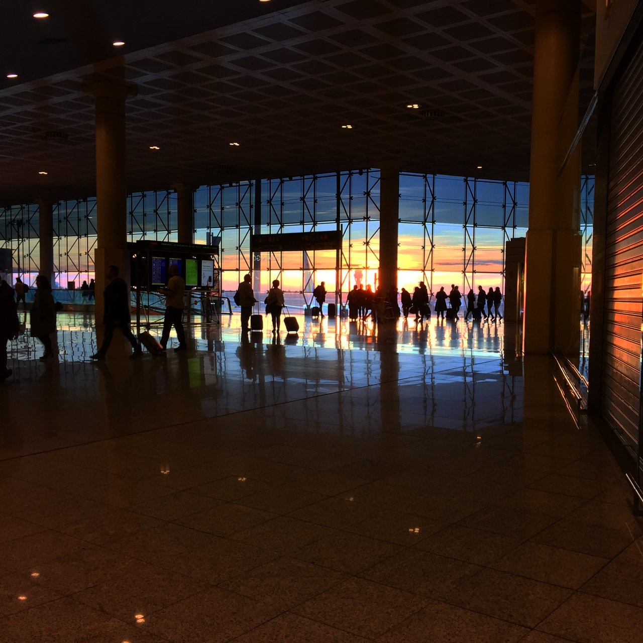 Airport terminal at sunset, travellers silhouetted against the glass wall
