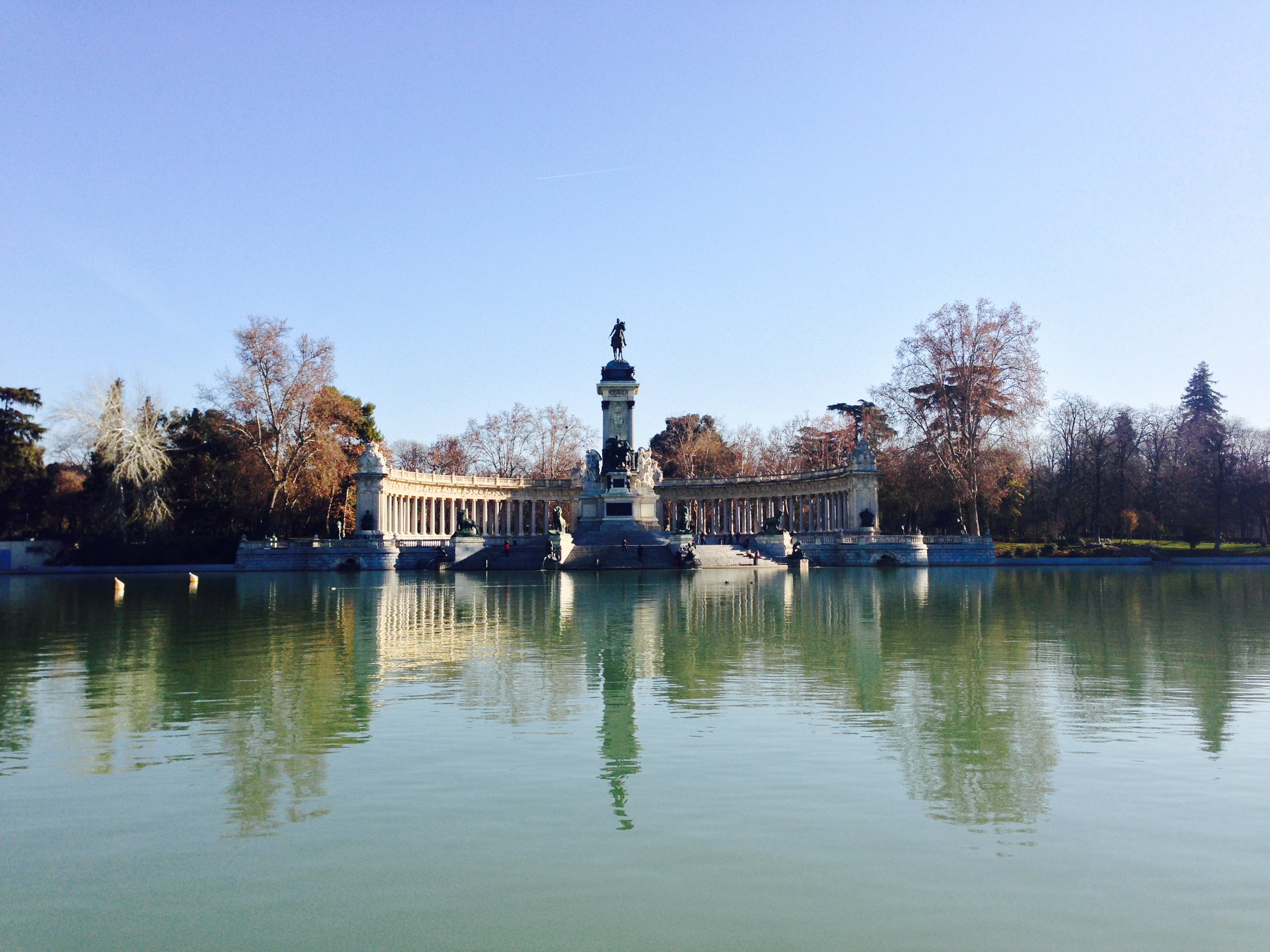 The Alfonso XII monument reflected in the still lake of El Retiro in winter