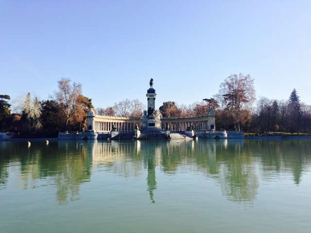The Alfonso XII monument reflected in the still lake of El Retiro in winter