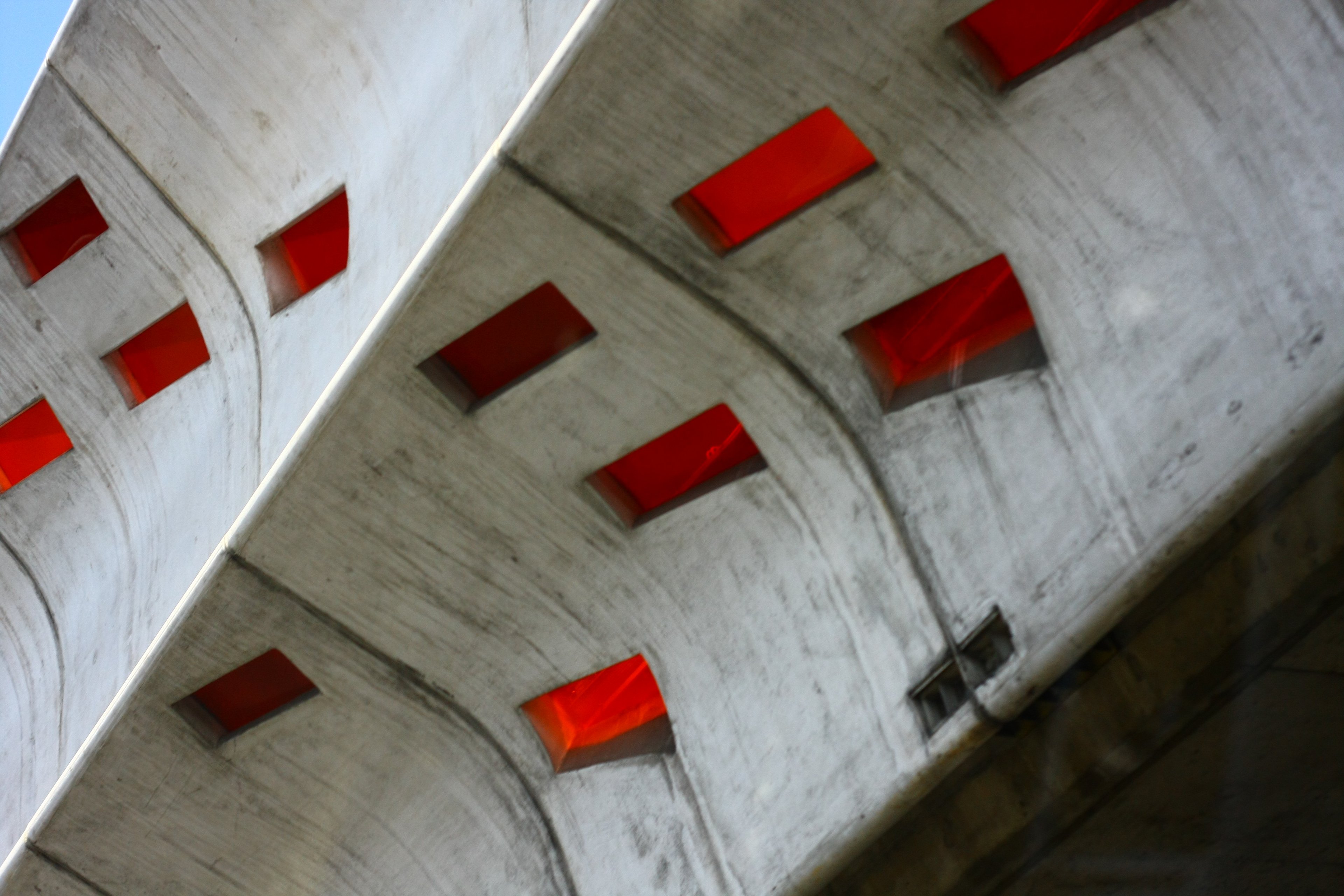 Concrete underpass ceiling pierced by rows of red glass skylights