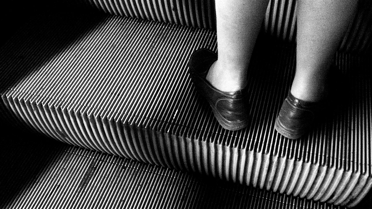 Feet on a ribbed escalator step, black and white