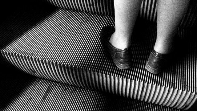 Feet on a ribbed escalator step, black and white