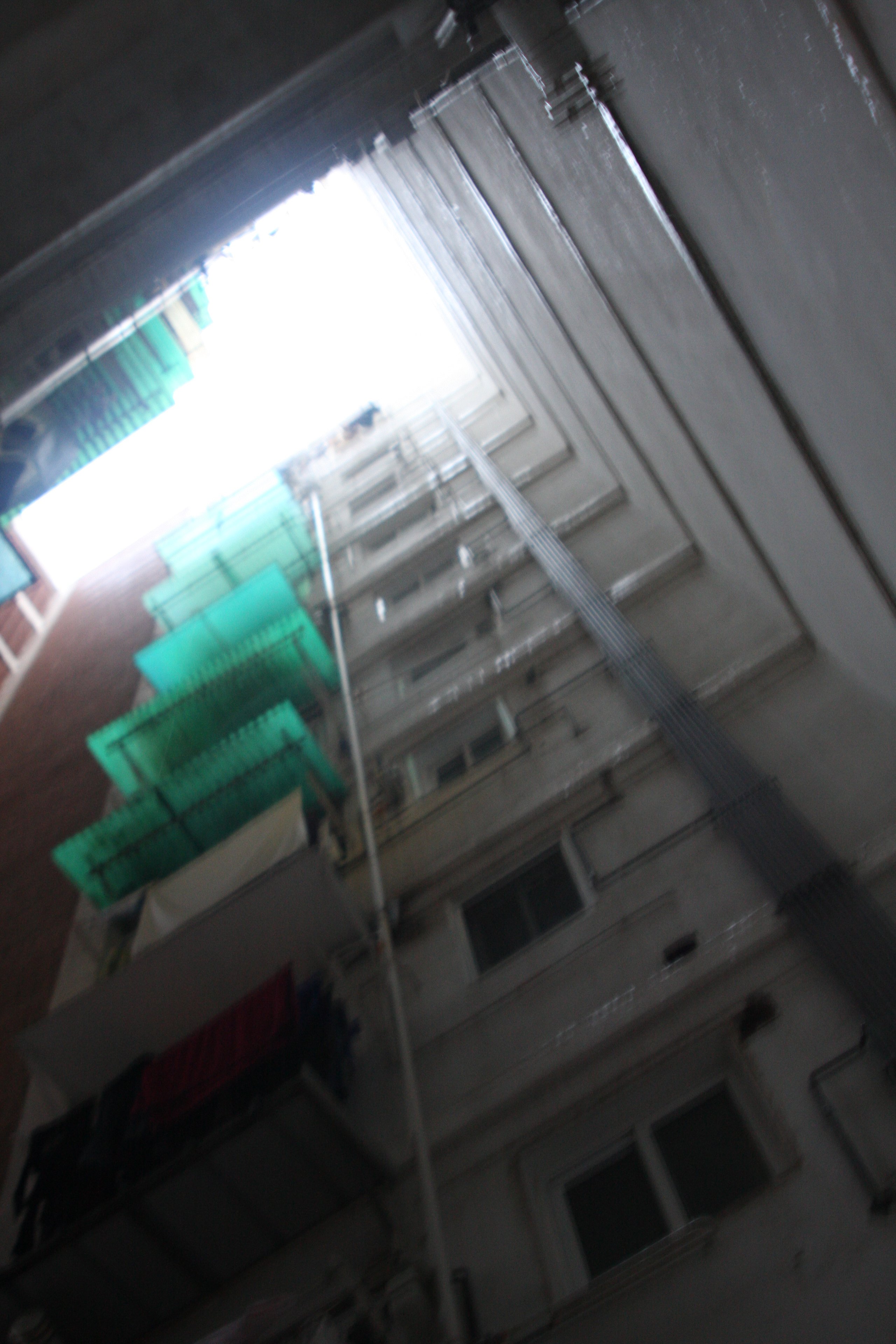 Looking up a residential facade with green shutters, the frame tilted and blurred