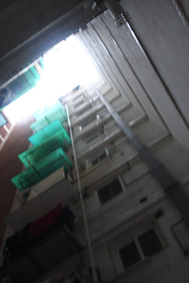 Looking up a residential facade with green shutters, the frame tilted and blurred