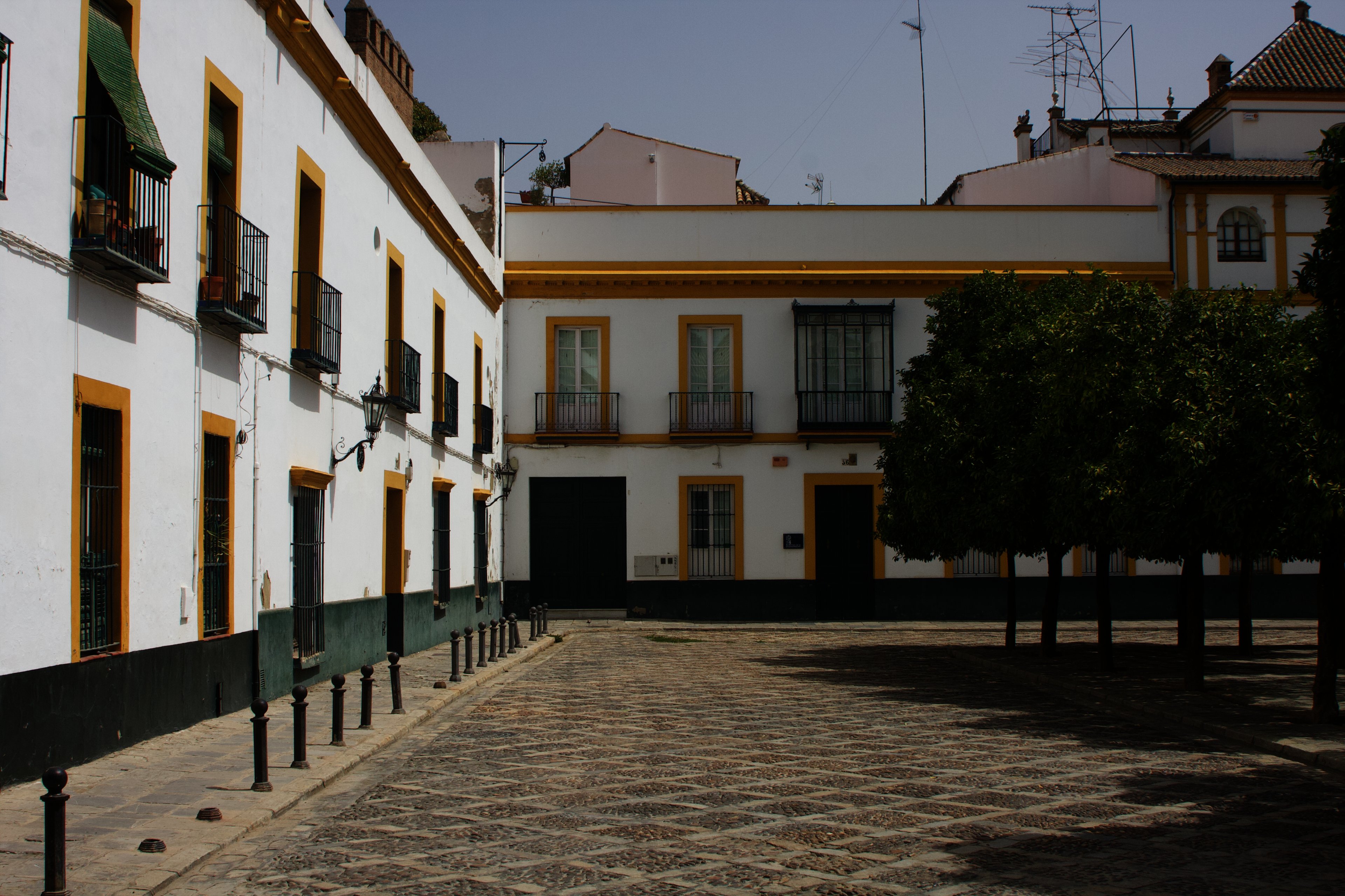 Whitewashed houses with ochre trim around a cobbled square with orange trees