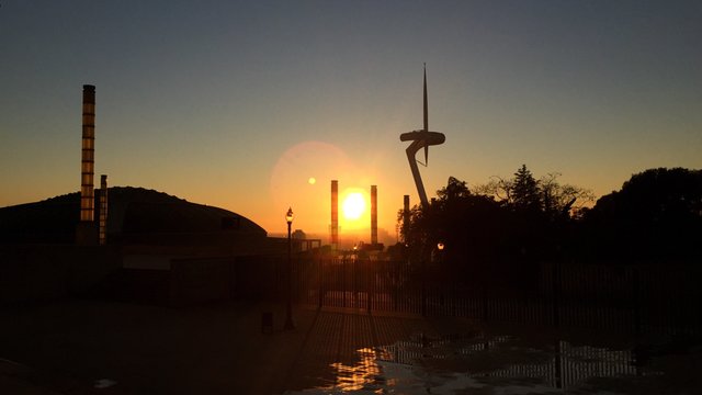 Sunset silhouetting factory chimneys and the Montjuïc communications tower